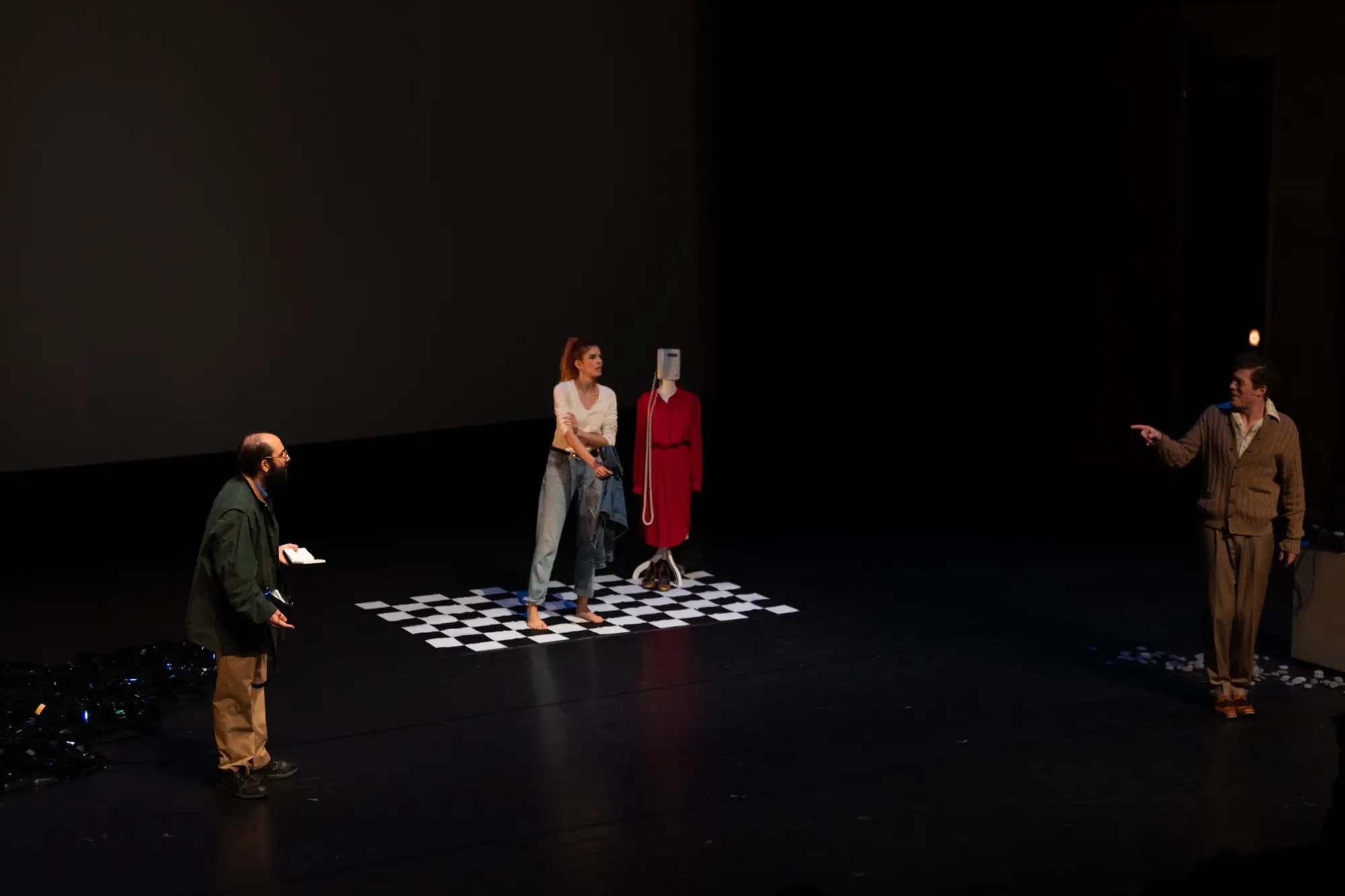 Performers face one another across a black stage