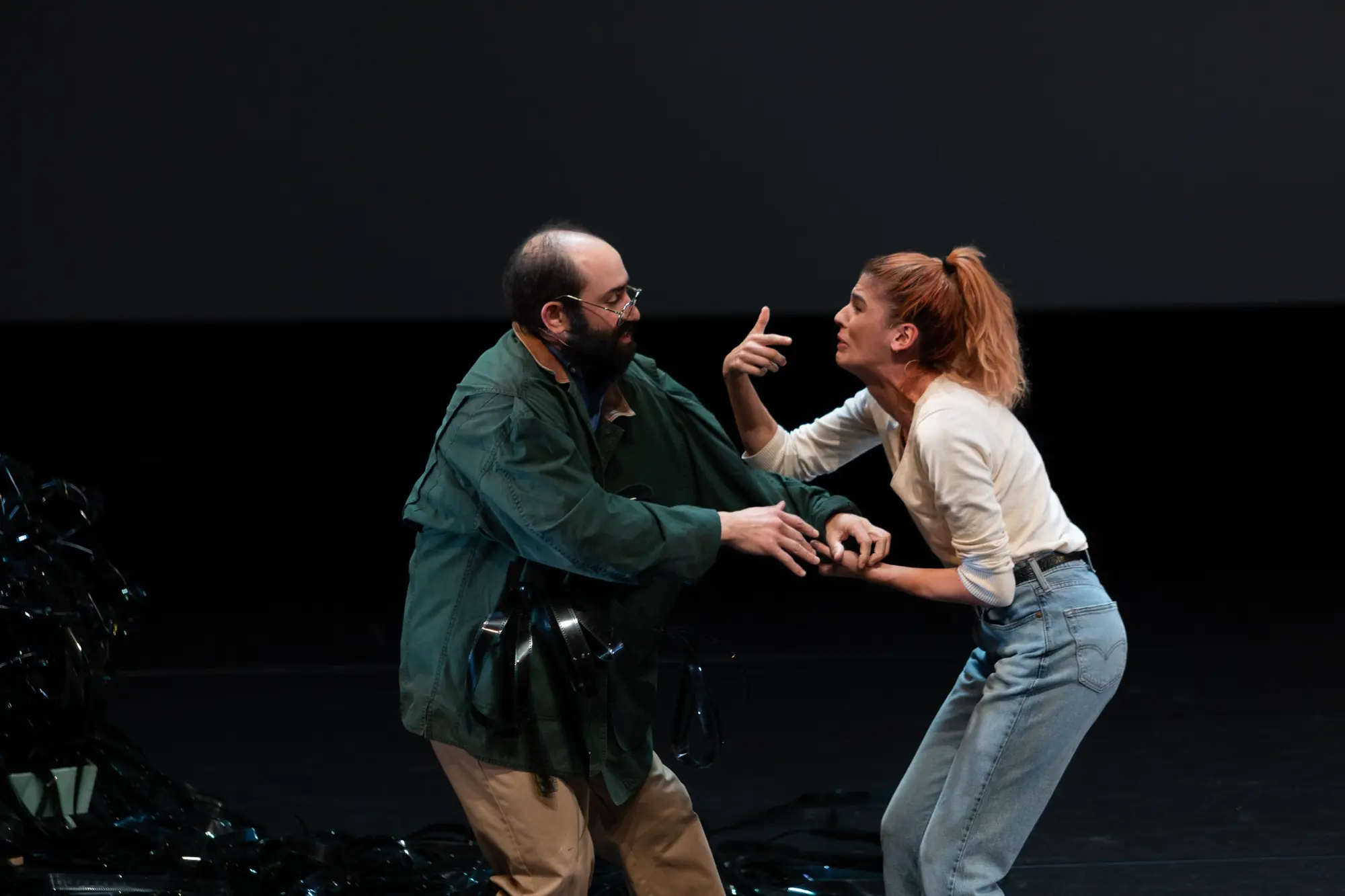Two performers struggle in a pool of white light