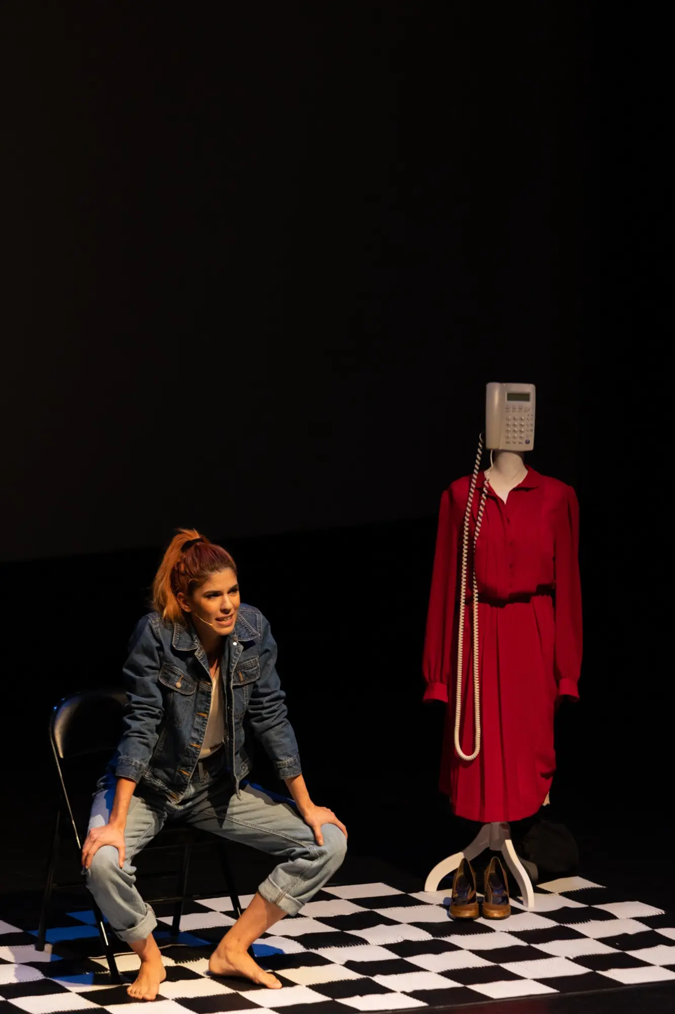 A woman kneels beside a mannequin on a checkerboard floor