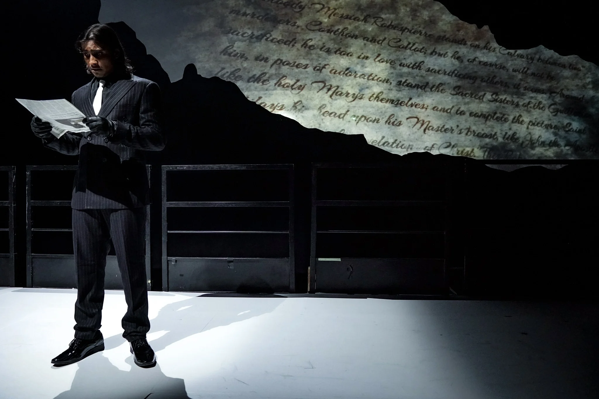 A performer reads beneath a projected handwritten text