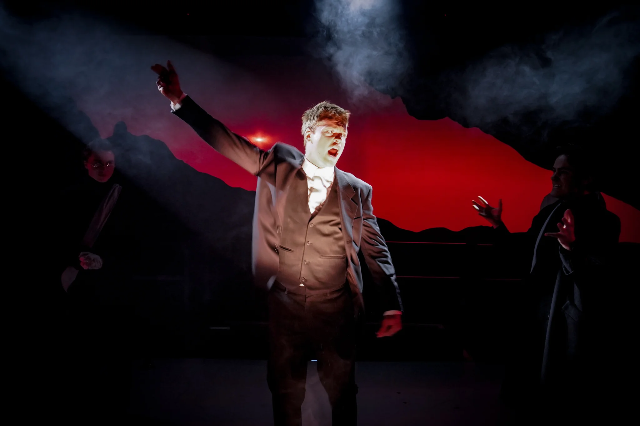 Danton raises his arms against a red projection