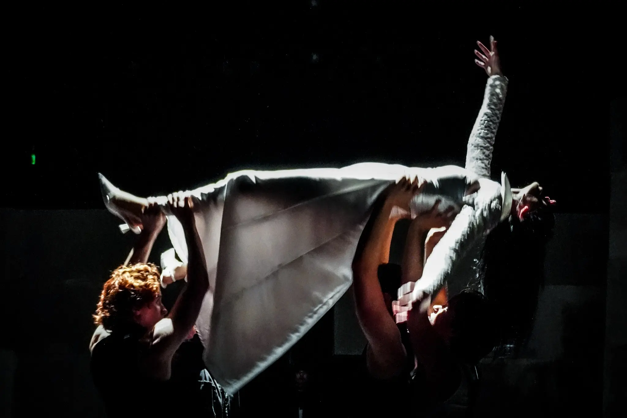 The company gathers in a severe theatrical landscape