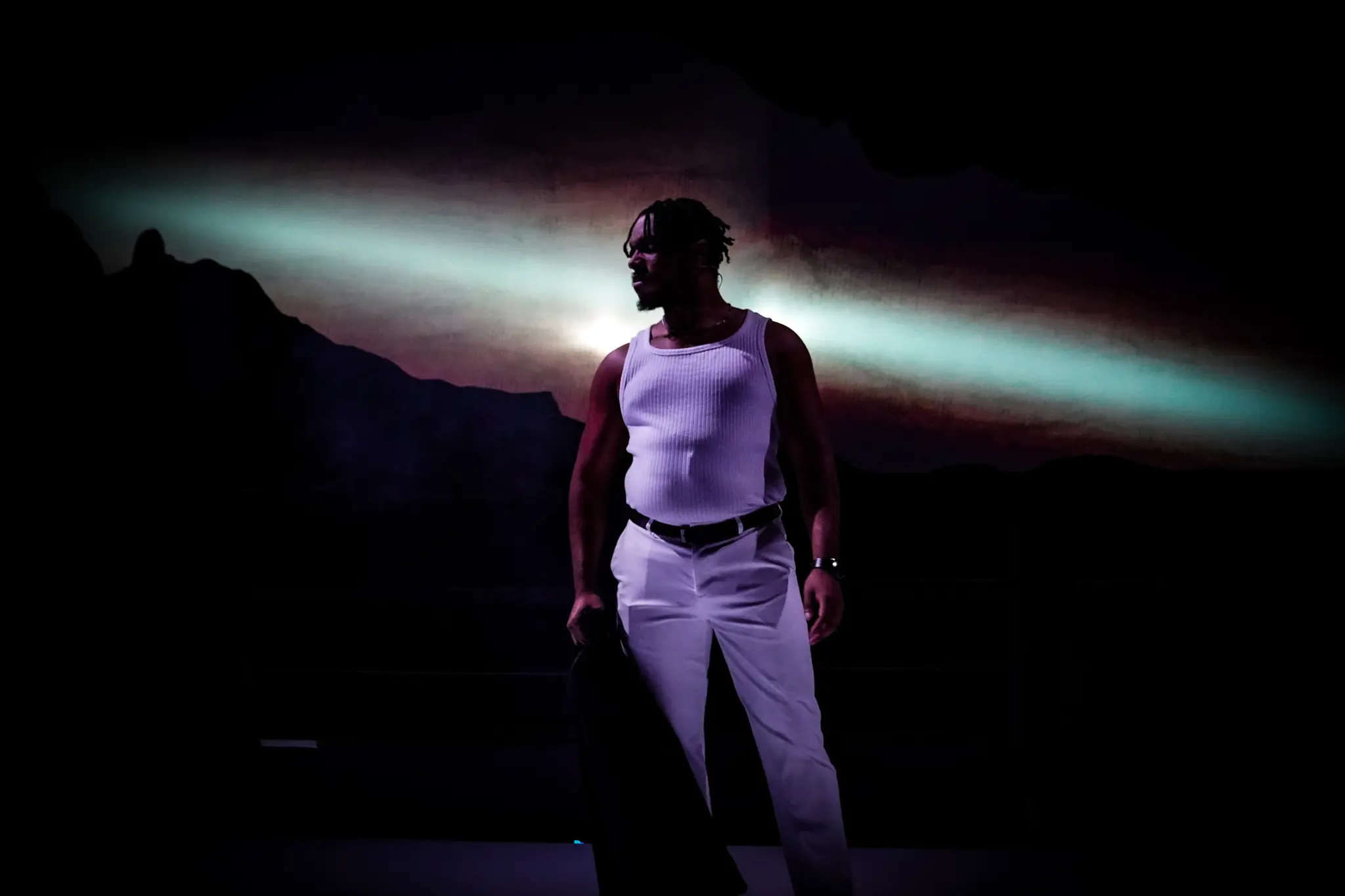 A performer stands within a field of projected light