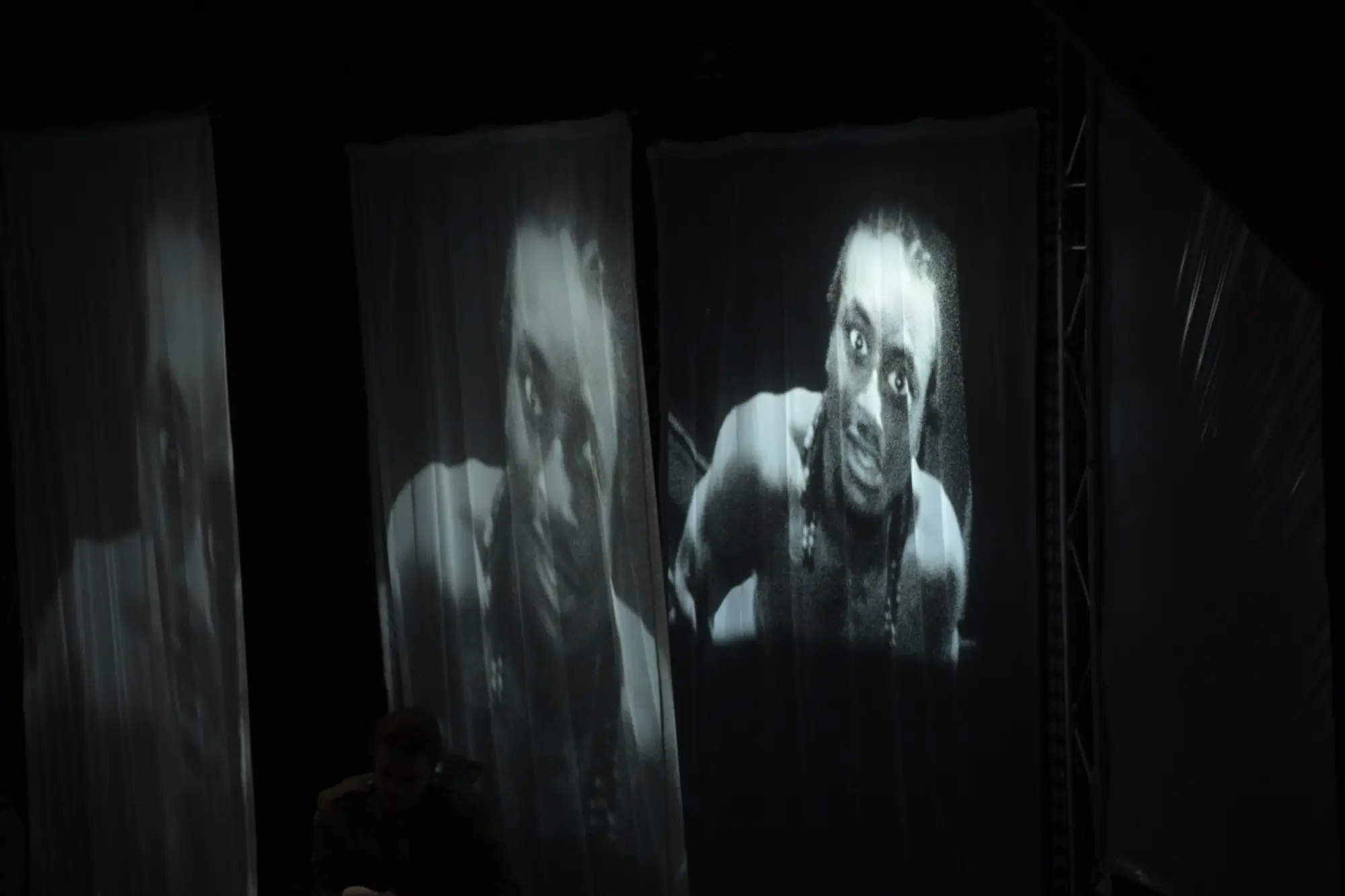 A ghostly face is projected across hanging fabric