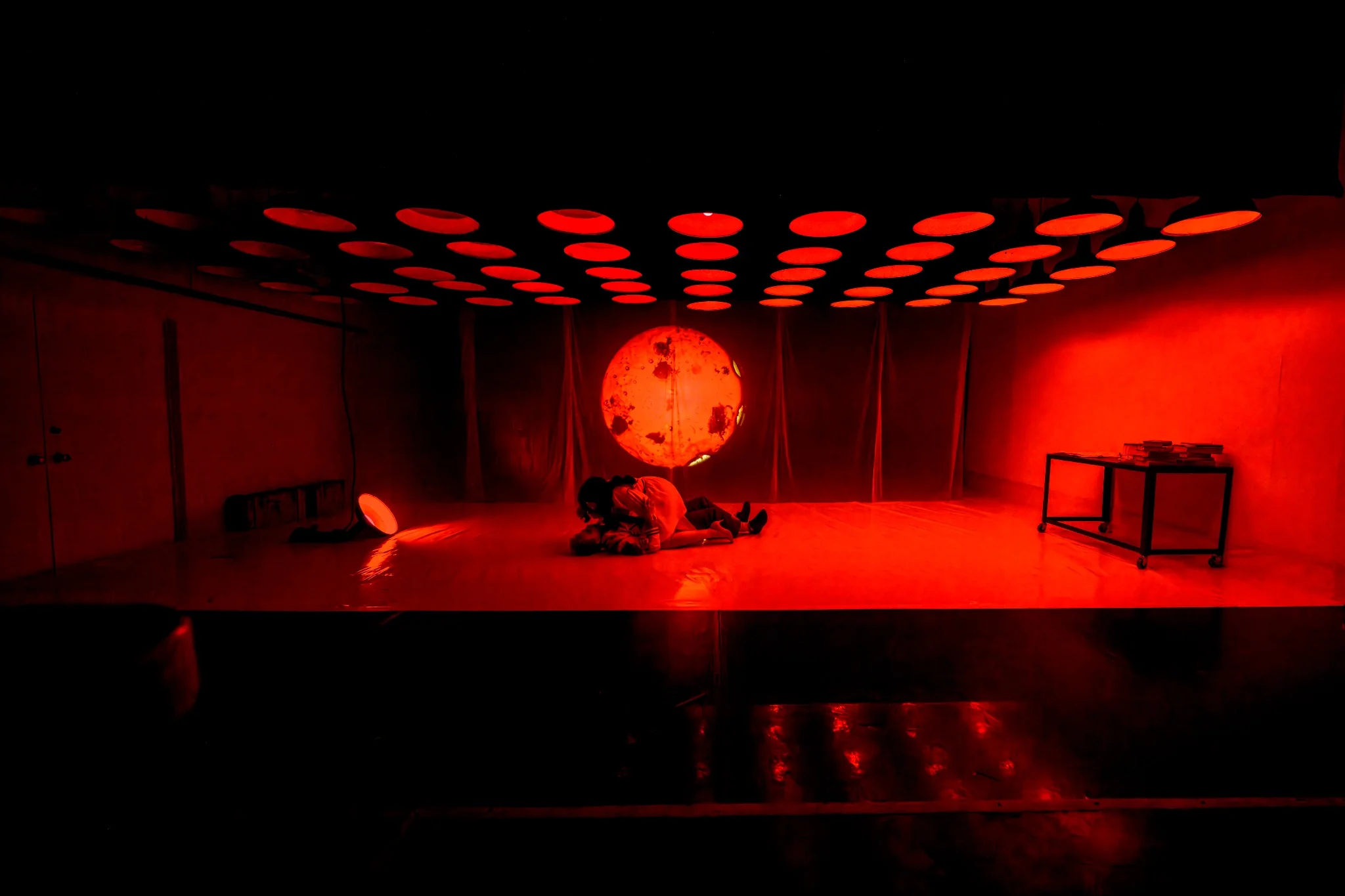 A red-lit laboratory beneath rows of circular lights