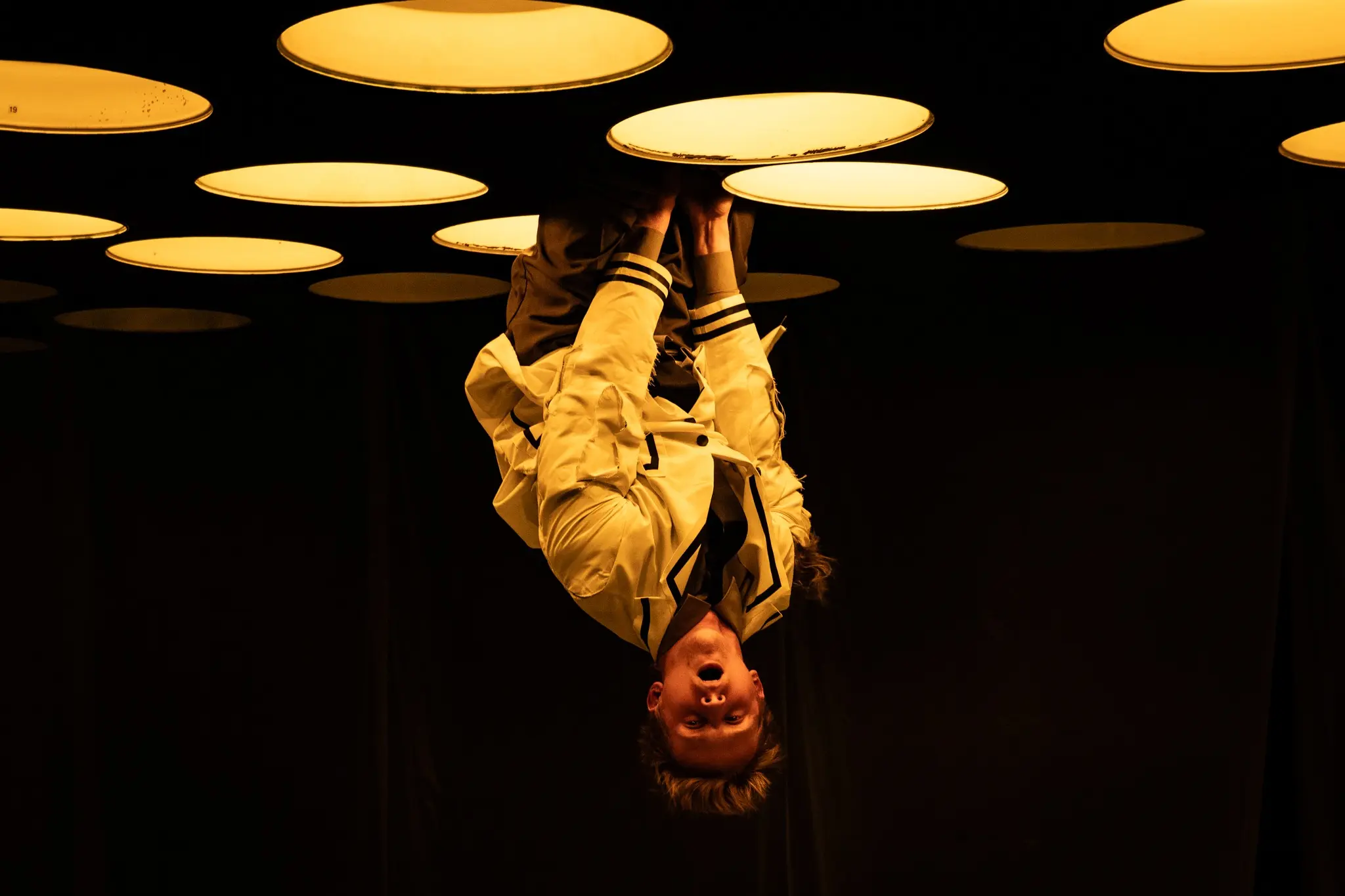 A scientist hangs upside down among circular laboratory lights