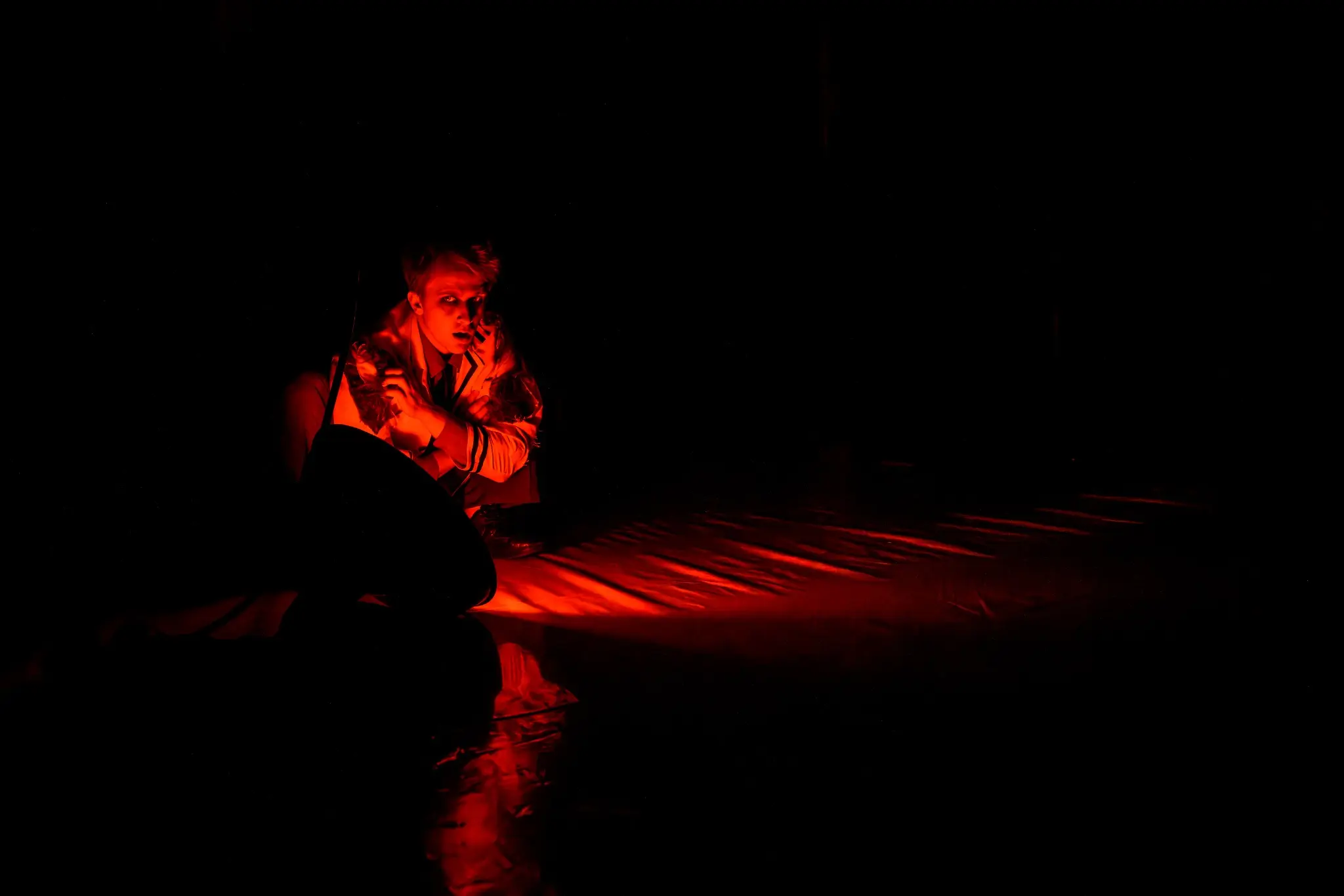 A scientist crouches in a narrow pool of red light