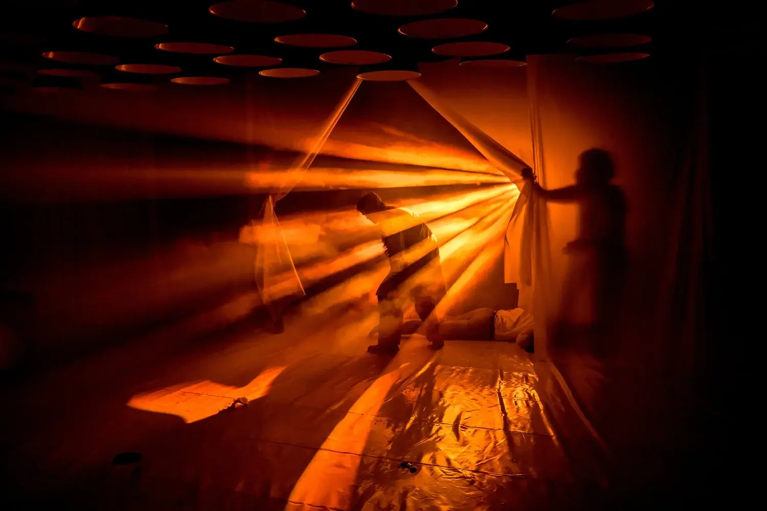 A performer is framed by amber beams of light