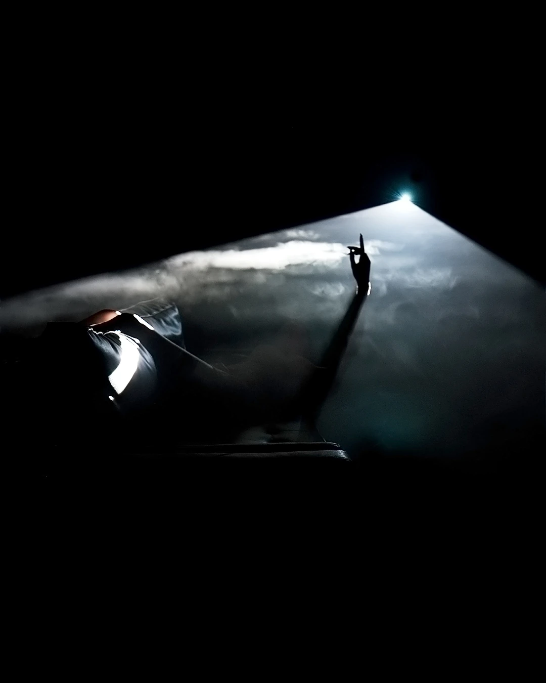 A performer reaches into a narrow beam of light