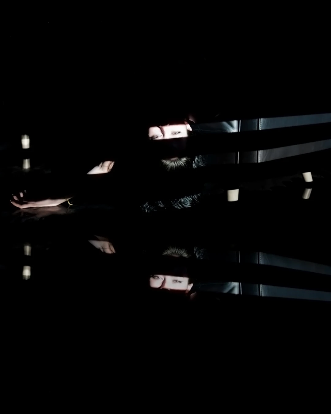 A performer's eyes appear between horizontal bands of light